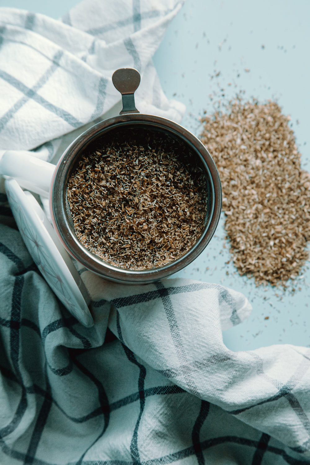 metal strainer with loose tea next to a tea towel