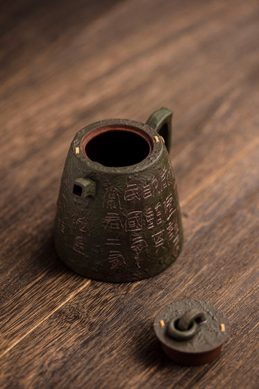 metal teapot sits with its lid off on a wooden surface