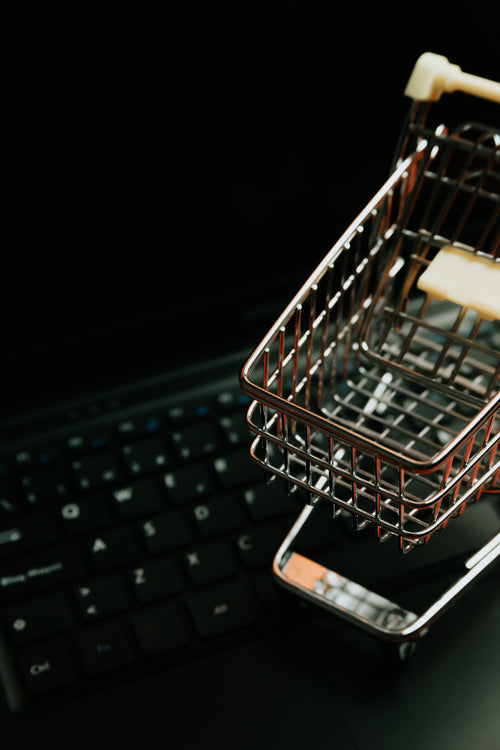miniature silver shopping cart on a black keyboard