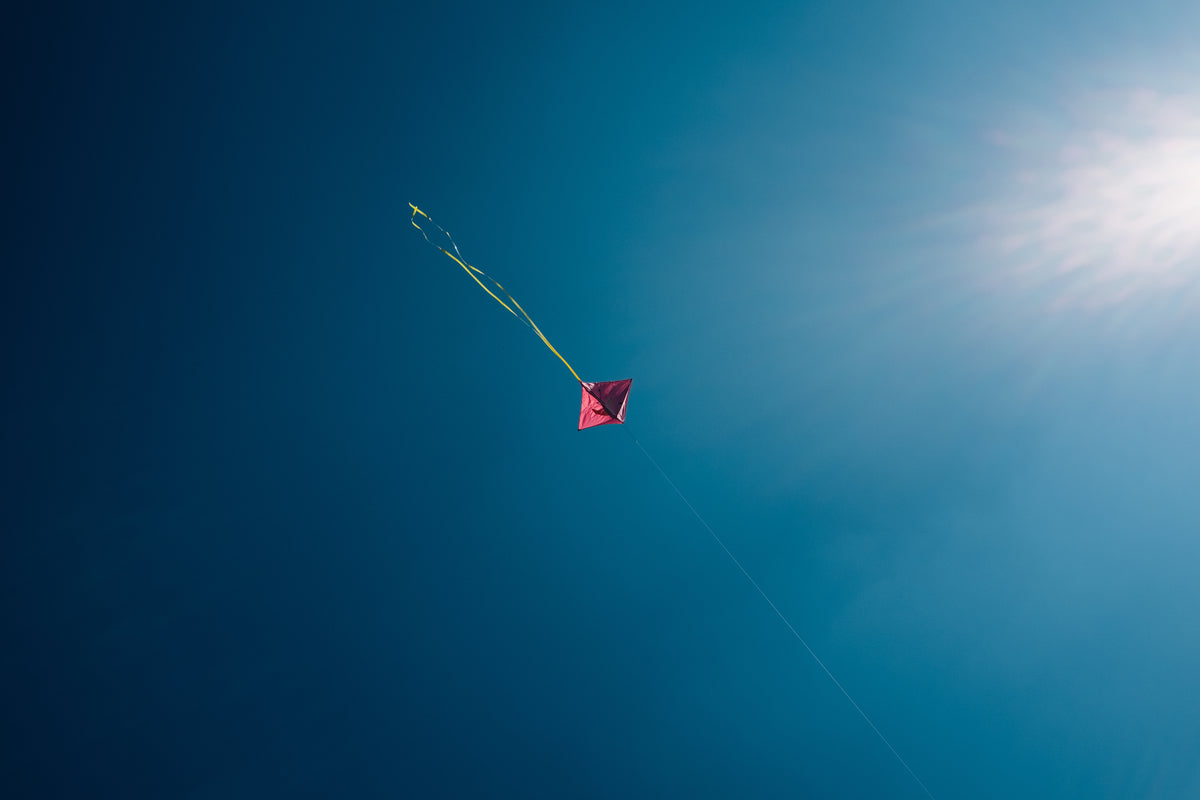 minimalist pink kite dots through blue skies