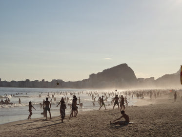 misty crowded beach with hills and buildings