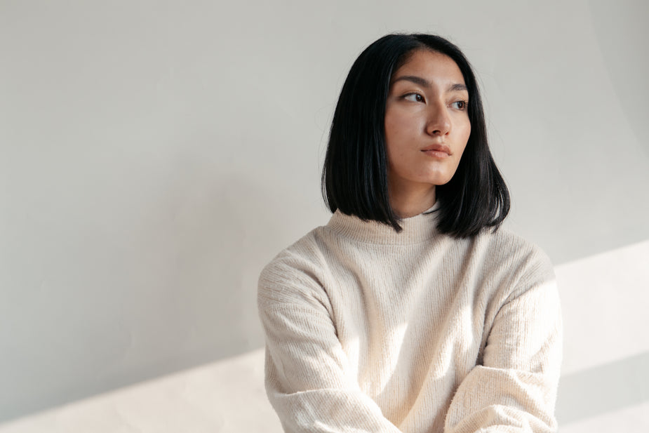 Model in neutral clothing by a window