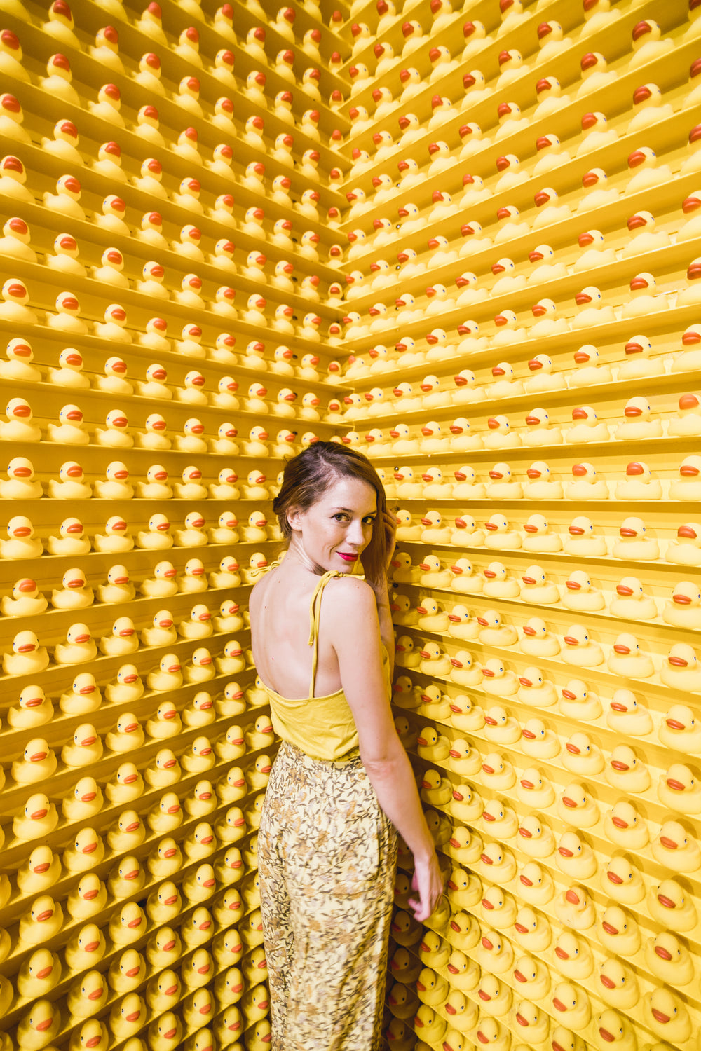 model posing coyly with hundreds of rubber ducks