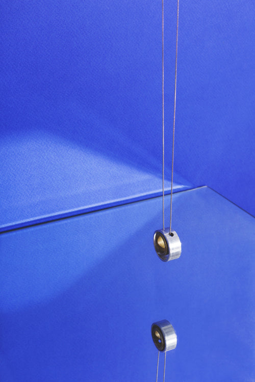 modern jewelry hanging on blue with reflection