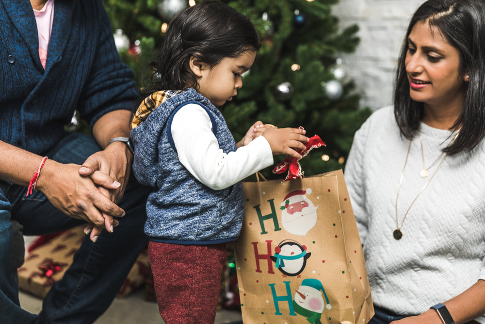 mãe e pai ajudam o filho a abrir o presente de natal