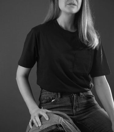 monochrome person sitting down in black shirt and blue jeans