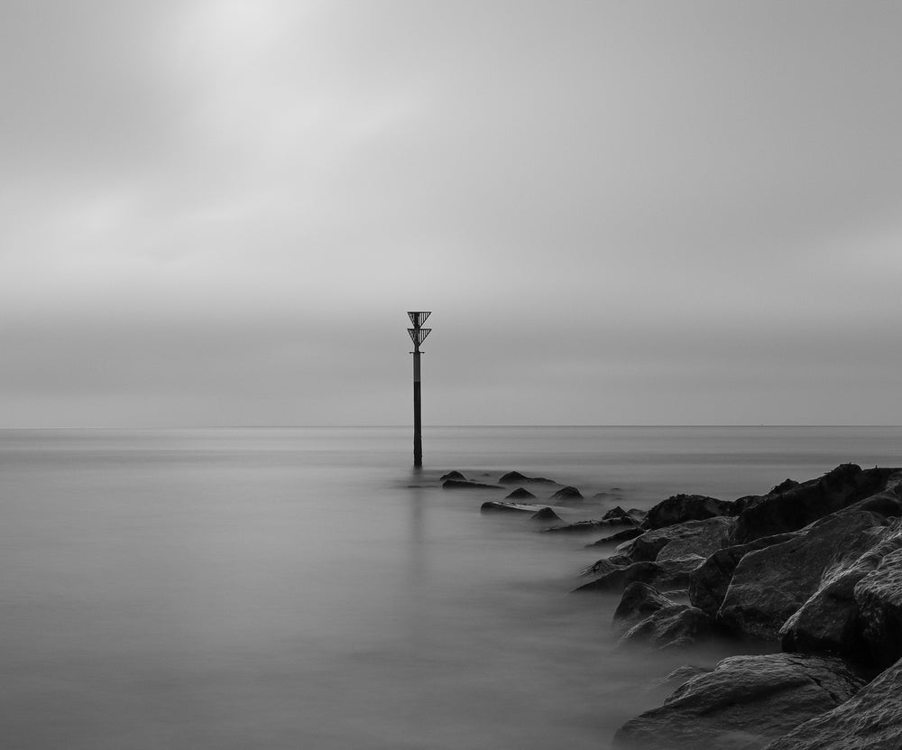 monochrome photo of rocks reaching out to water