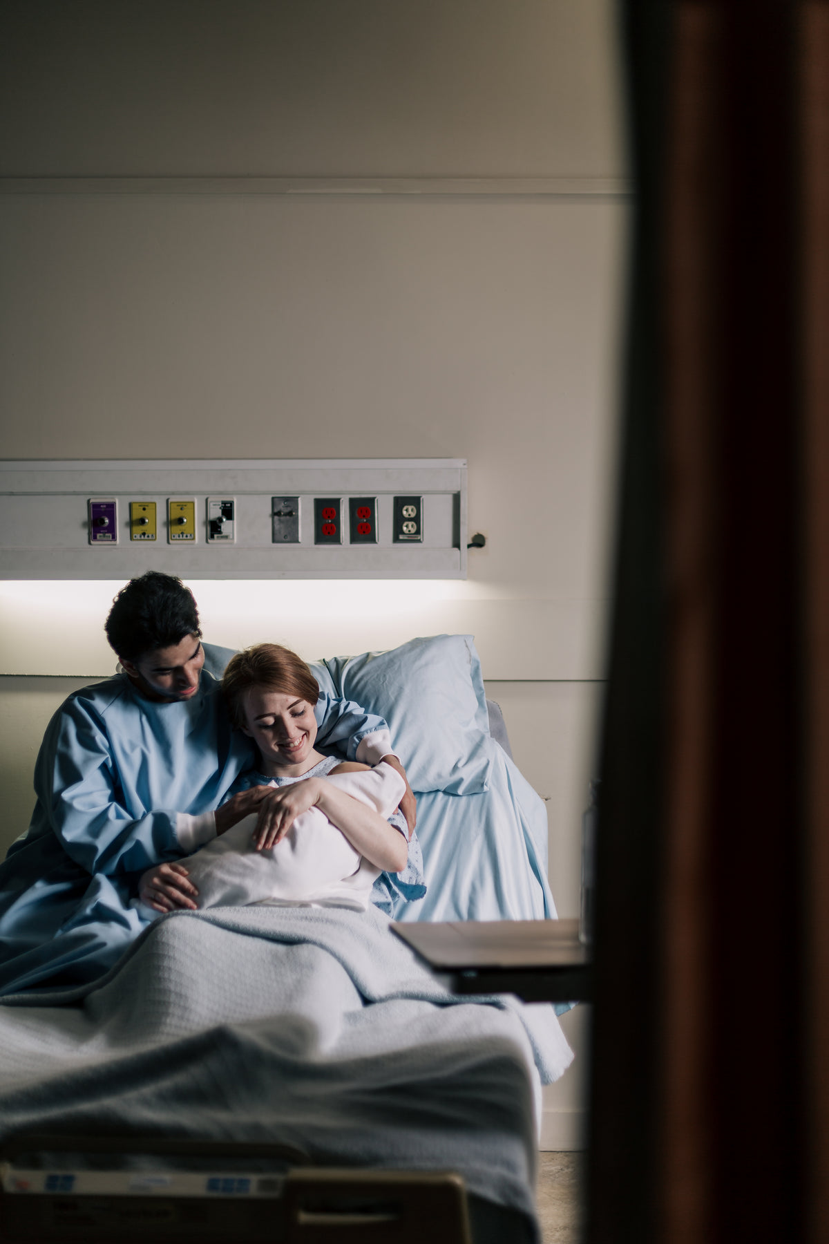 母亲和父亲在病床上拥抱新生儿