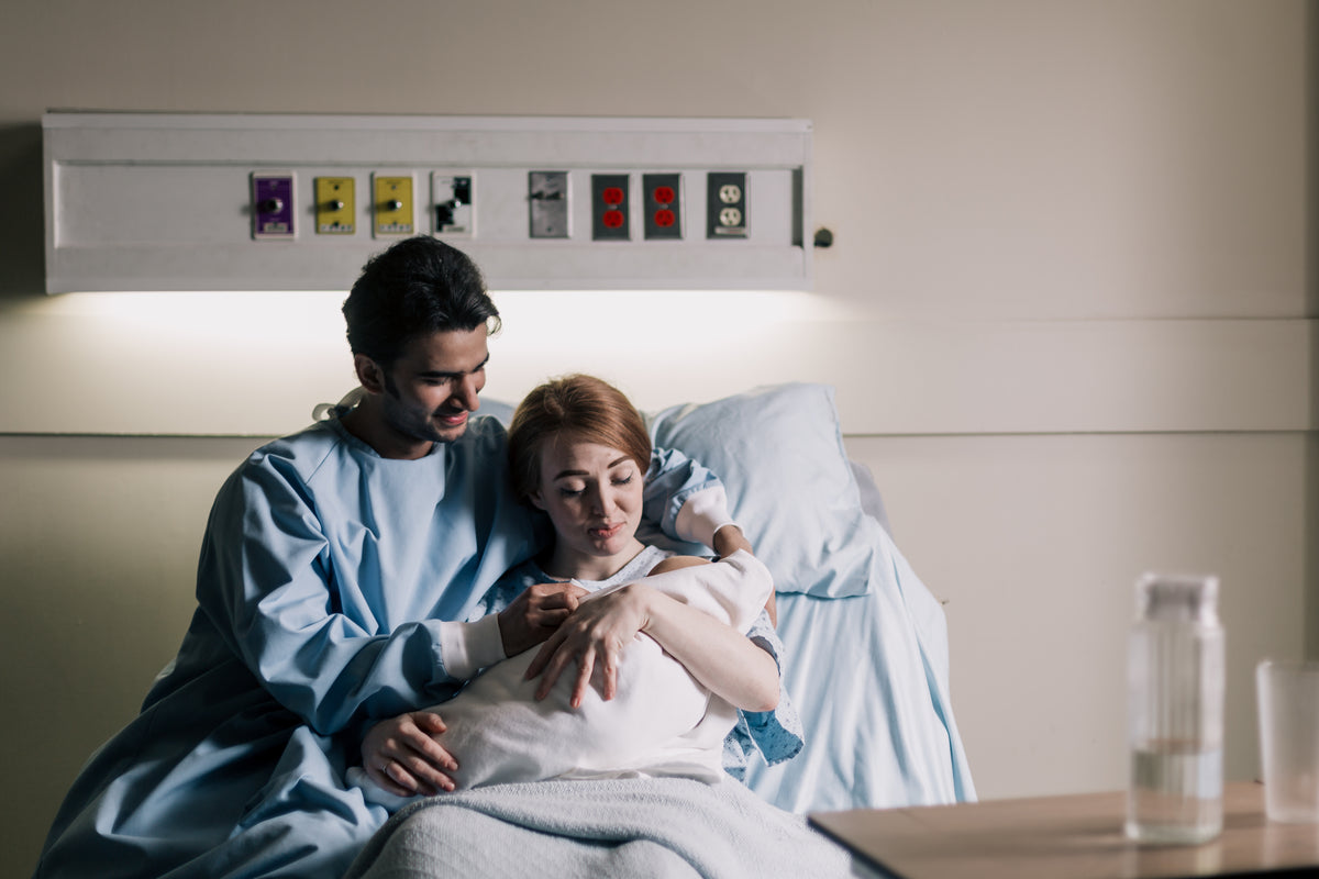 母亲和父亲坐在病床上欣赏新生儿