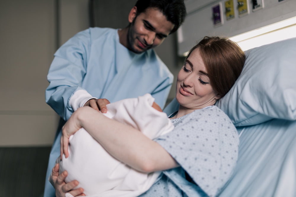 mother and father smiling down on their newborn baby