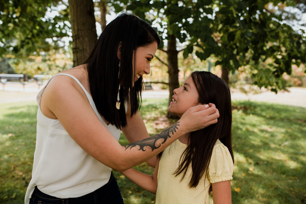 mother looks at child and moves their hair