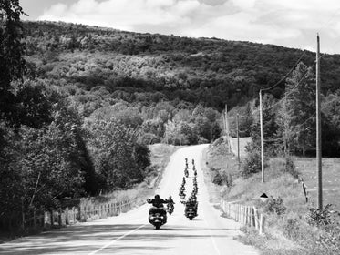 motorcycle caravan rides hillside in black and white