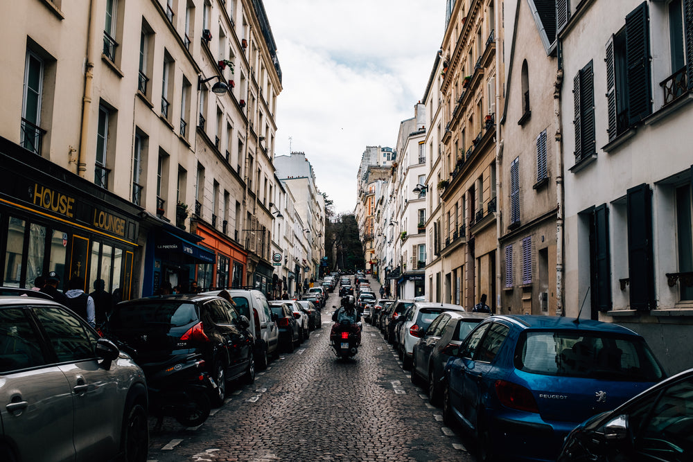 motorcycle rides up narrow cobblestone street