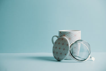 mug with a lid and strainer sits against a blue background