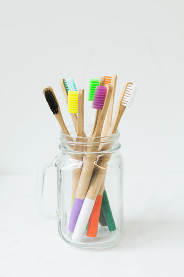 multi-colored toothbrushes in glass
