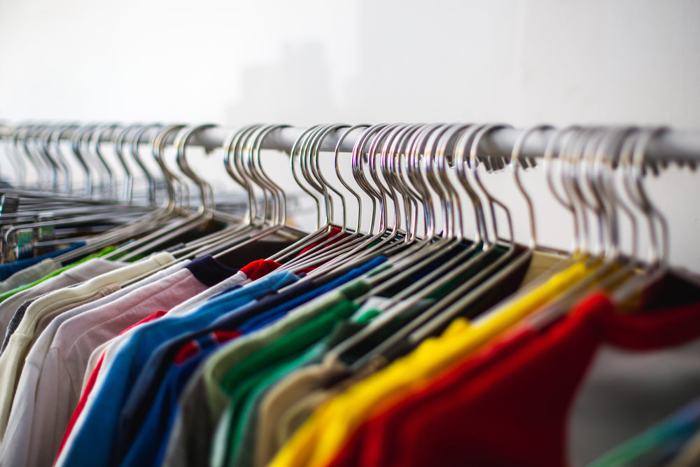 multiple colored shirts along a rail