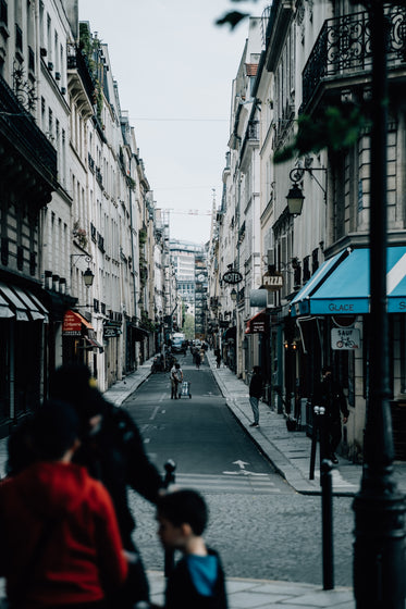 narrow city street with people walking through the center