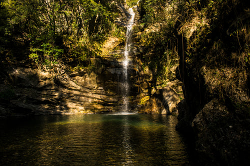 narrow waterfall into tropical pool