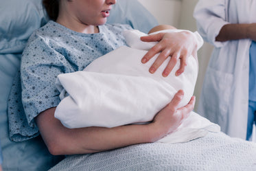 new mother in hospital gown embraces her baby