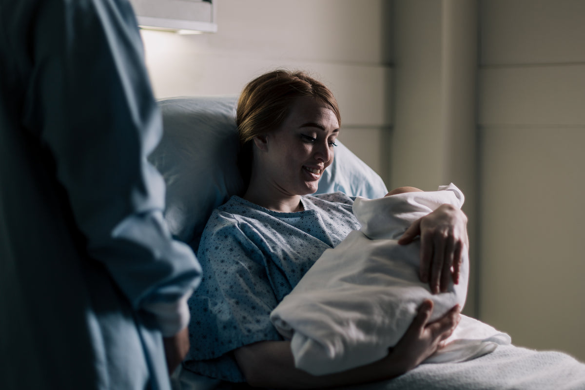 新妈妈躺在医院的病床上微笑着看着她的宝宝