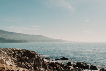 ocean mist crawls across the water reaching rocky shores