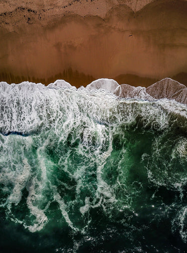 ocean waves meet red sands aerial