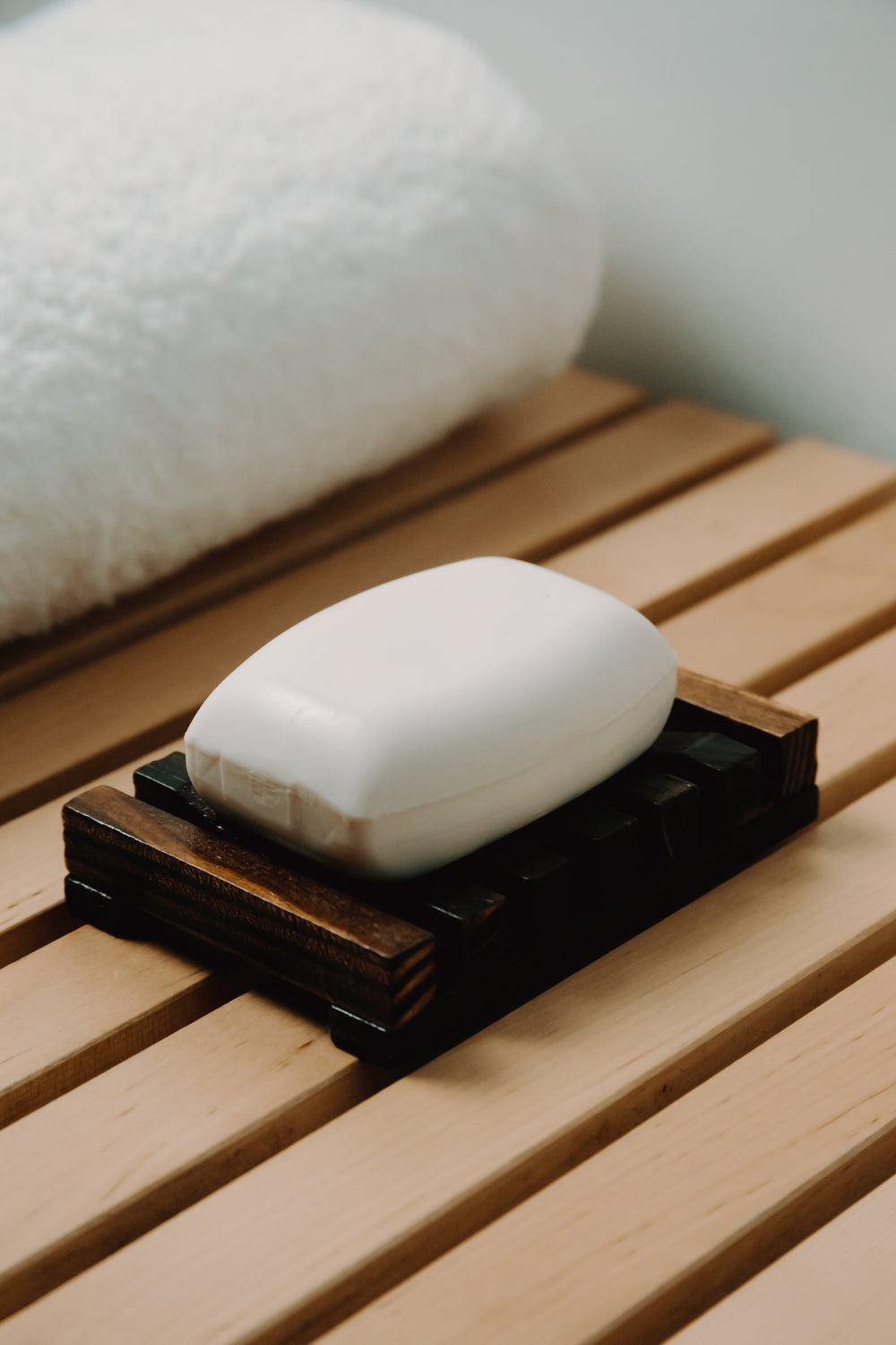 one bar of white soap lays in a wooden holder