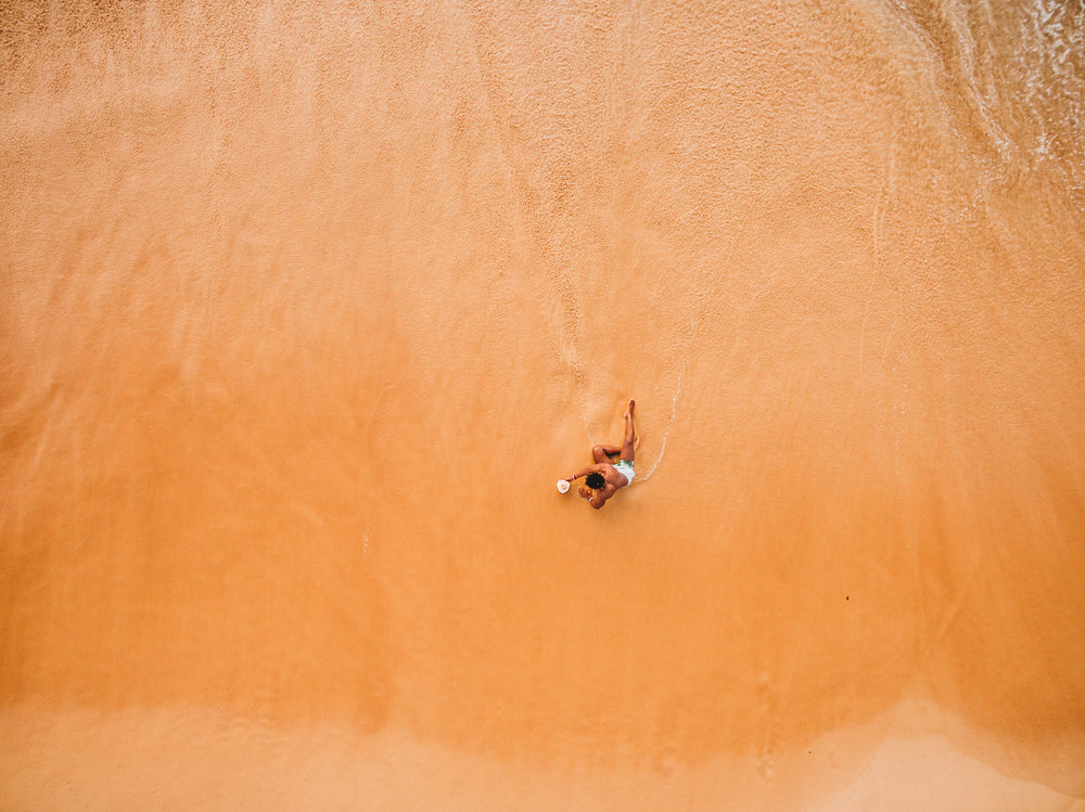 um homem relaxando na praia à beira da água
