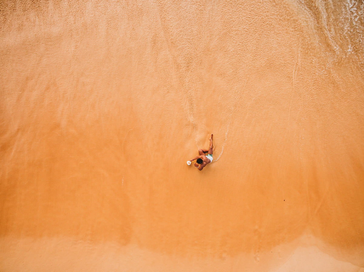 um homem relaxando na praia à beira da água