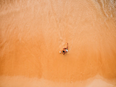 one man lounges on the beach at the water's edge
