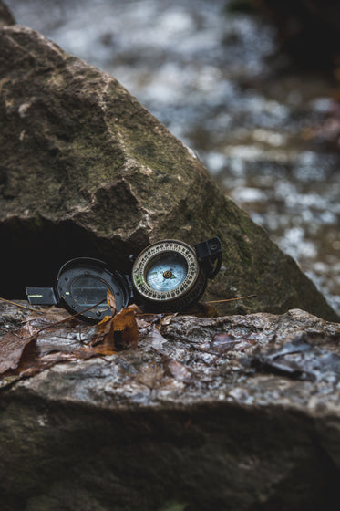 open compass resting on the rocks