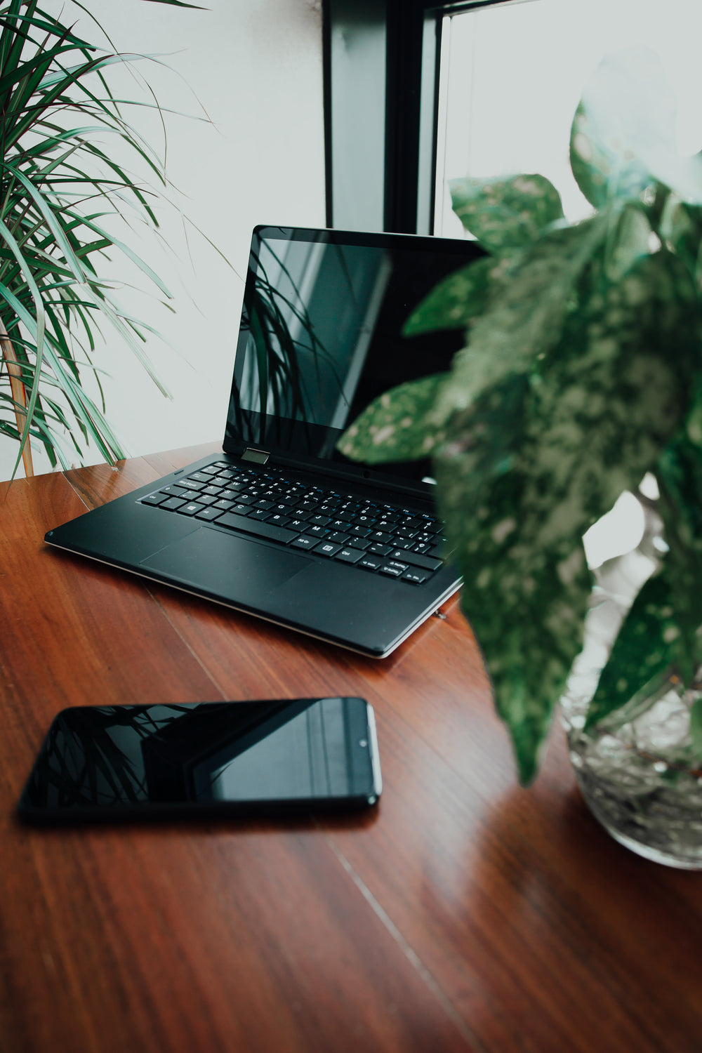 laptop aberto e celular sobre mesa