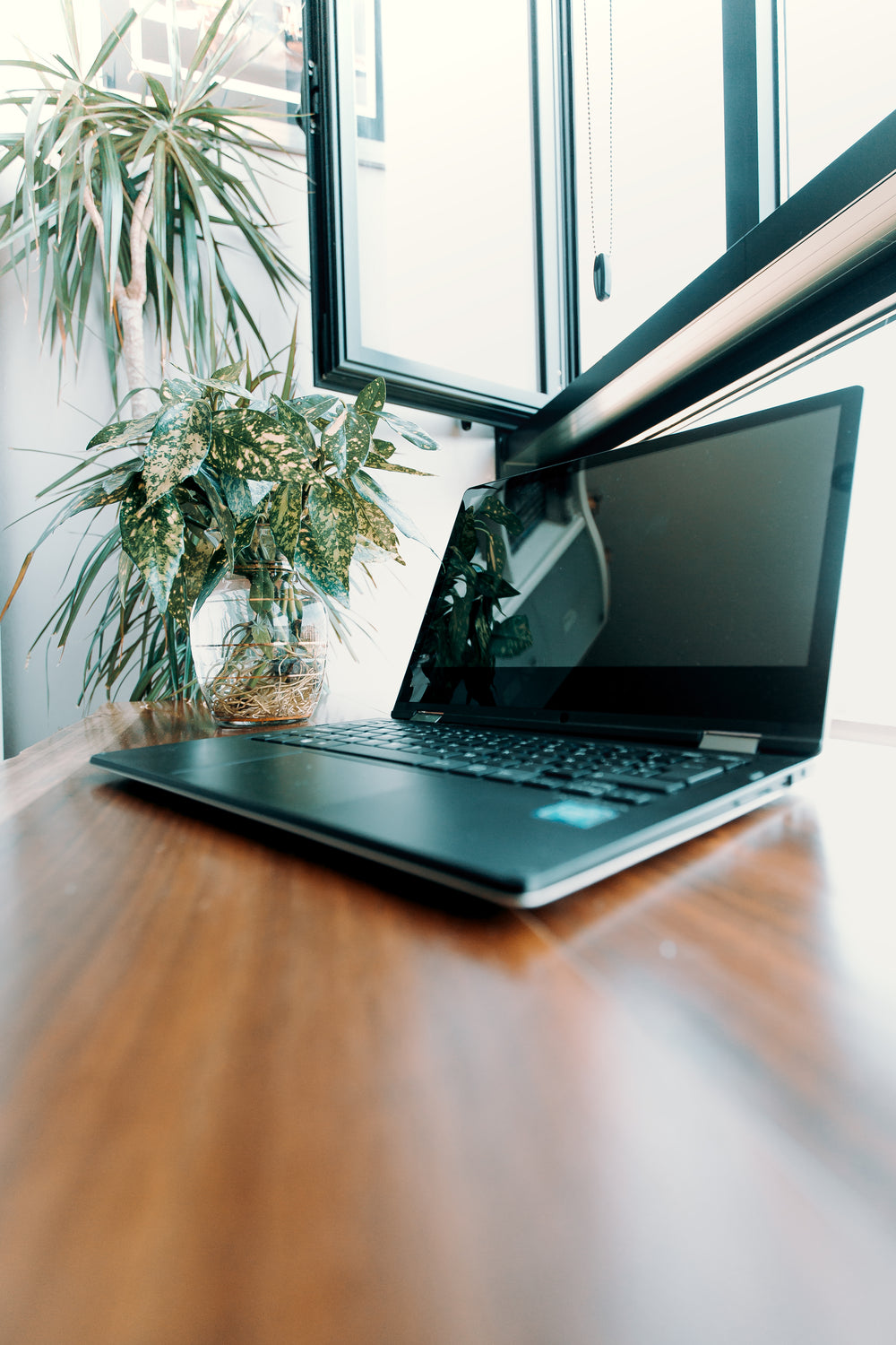 open laptop on a wooden desk under window