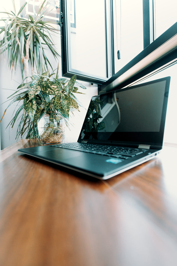 Open Laptop On A Wooden Desk Under Window