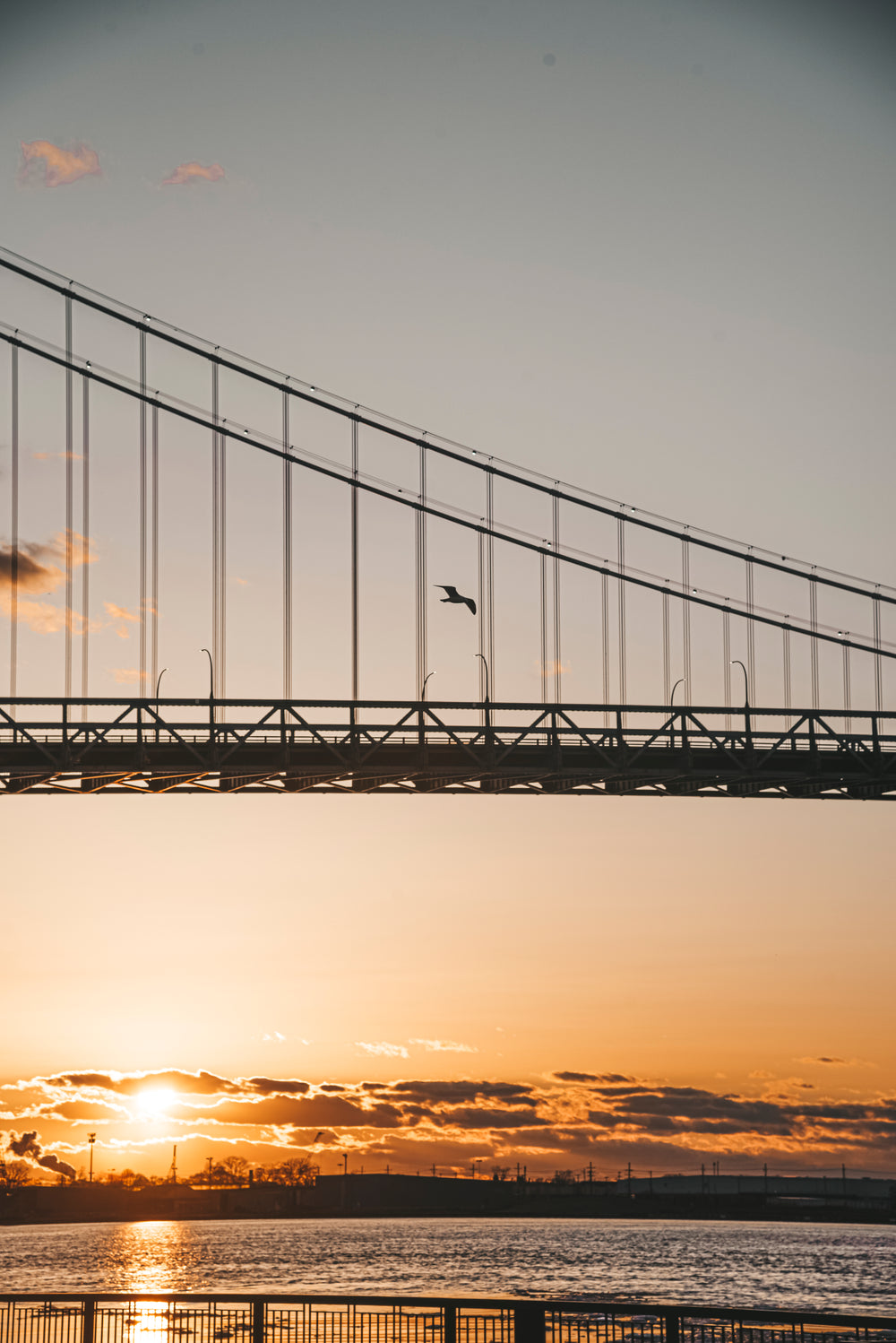 orange and yellow sky over water and part of a bridge