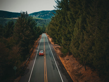 orange car drives down a paved country road