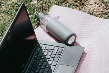 outdoors laptop and water bottle lay on pink yoga mat