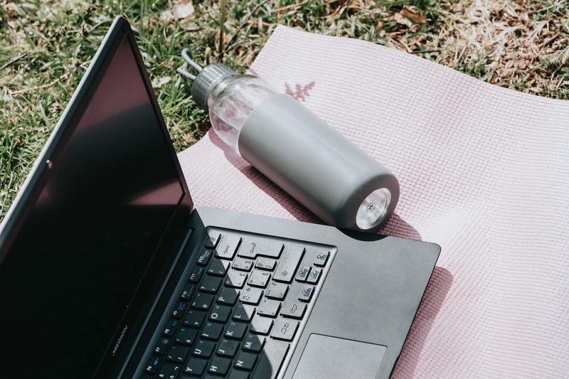 a laptop computer and a laptop computer - outdoors laptop and water bottle lay on pink yoga mat