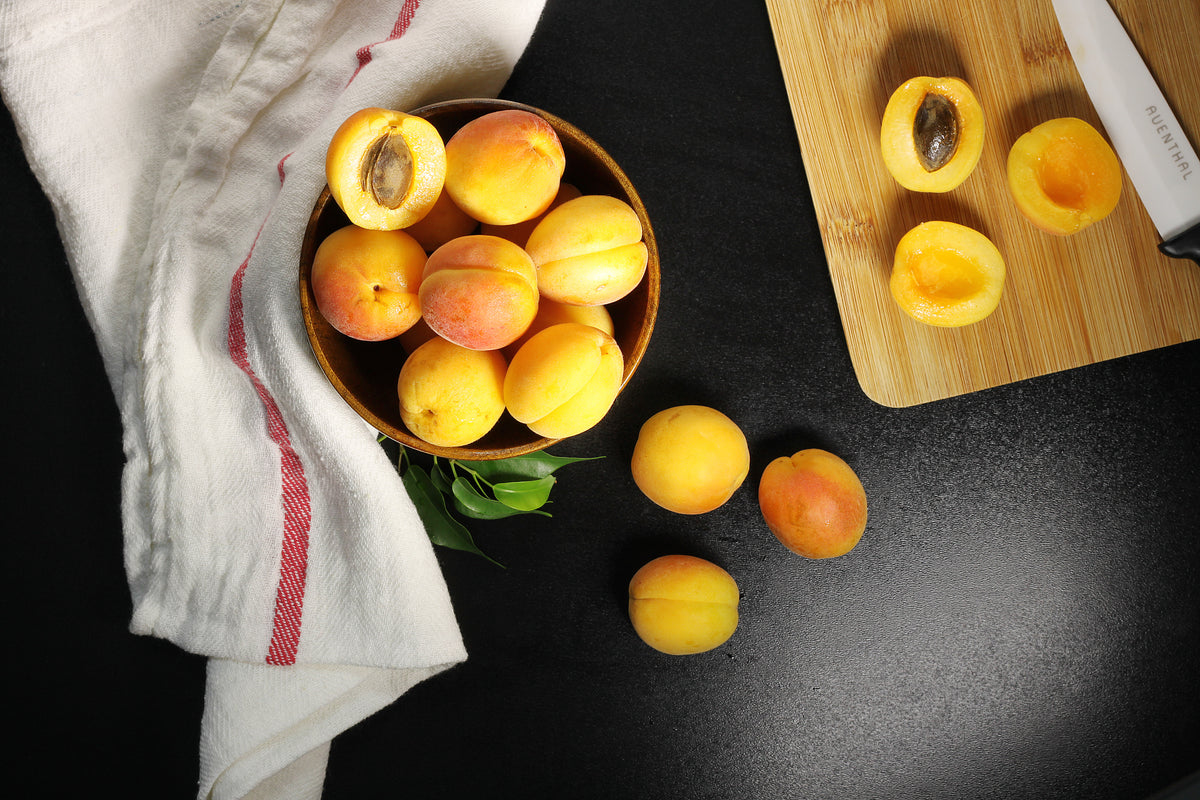 overhead shot of fresh apricots being halved and pitted