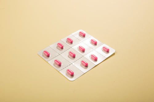packaged pink pills on dusty yellow