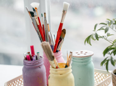 painted mason jars with a variety of craft supplies