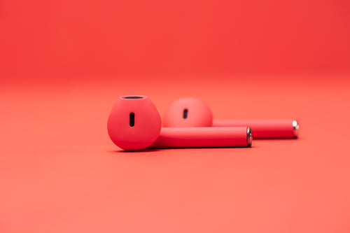pair of red earbuds on red surface