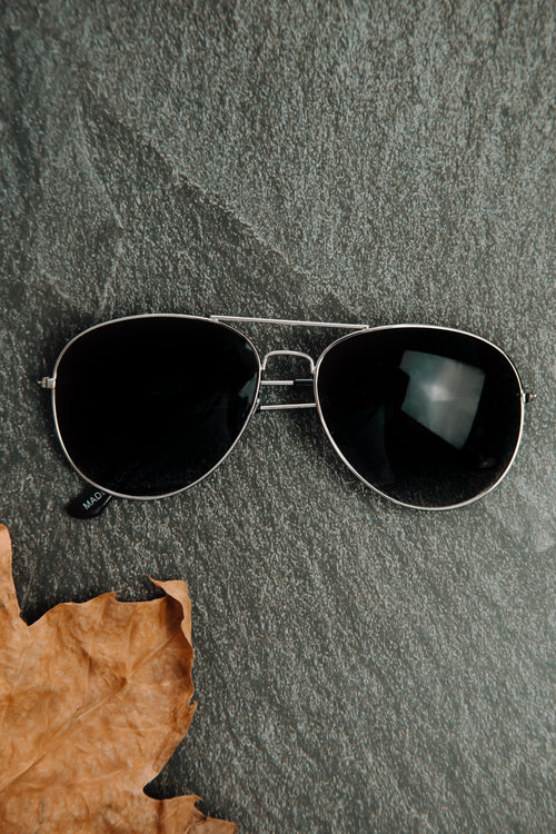 pair of silver framed sunglasses on a stone surface