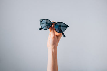 pair of sunglasses held in front of grey background