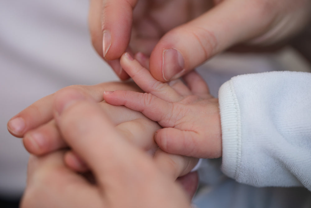 parent holding infant hand