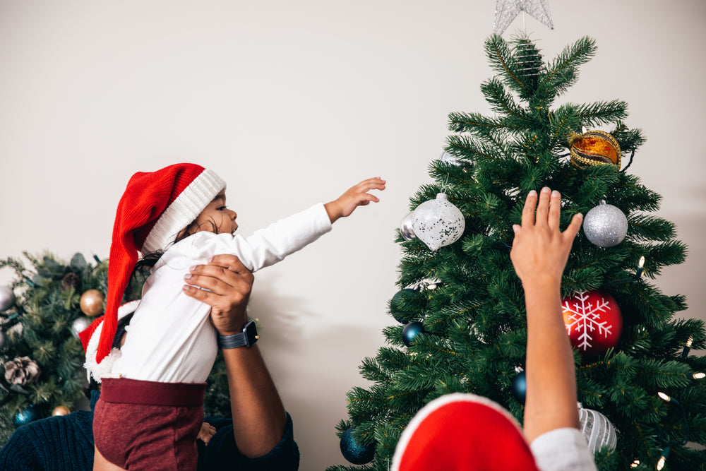 pais ajudam o filho na decoração da árvore de natal