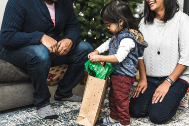 parents watch toddler opening christmas presents