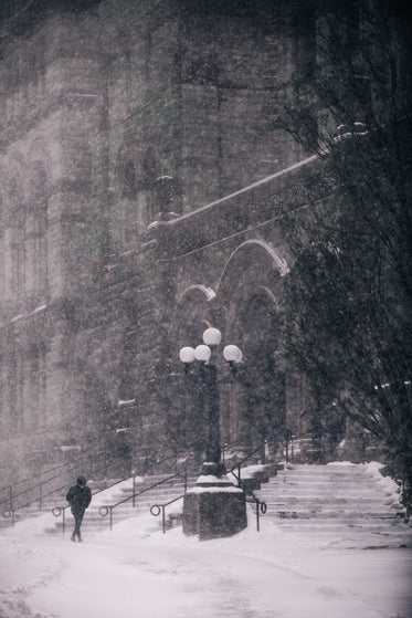 pedestrian passing through grey cityscape in blizzard