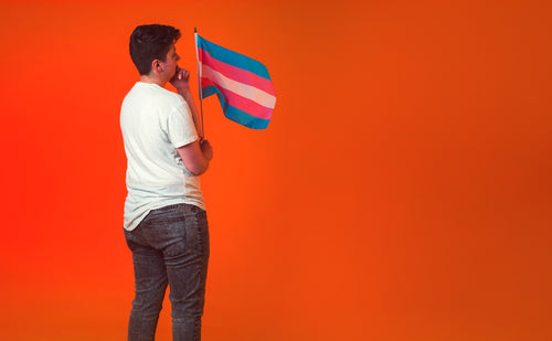 pensive androgyne holding trans pride banner