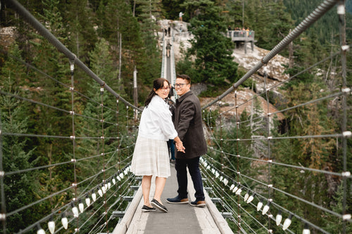 people hold hands walking down a suspension bridge